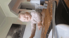 a baby is playing with a plate of food on a wooden table