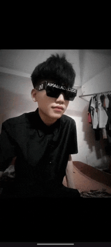 a young man wearing sunglasses and a black shirt with the letter j on it