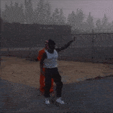 a man in a white tank top is pointing at something while standing next to another man in orange jumpsuit .