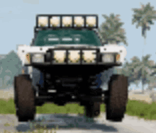a monster truck is driving down a road with palm trees in the background .