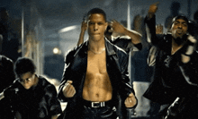 a man without a shirt is dancing in a group of men