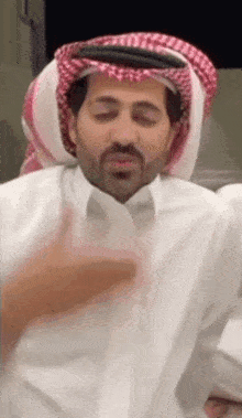 a man with a beard wearing a white shirt and a red and white scarf .