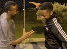 a young boy wearing an adidas jacket is standing next to a man