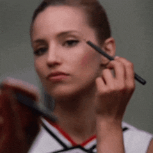 a woman is applying makeup to her eyebrows with a brush