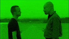 two men standing next to each other in a field with a green background
