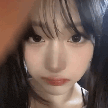 a close up of a girl 's face with long black hair and a fringe .