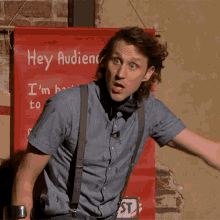 a man is standing in front of a red sign that says hey audience