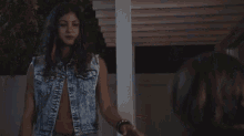 a woman in a denim vest is standing next to a woman in a denim vest .