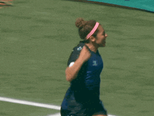a female soccer player wearing a number 1 jersey and a pink headband is kicking a ball .