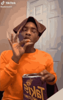 a man in an orange shirt is holding a can of sixast corn