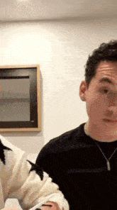 a man in a black sweater is sitting in front of a mirror in a room .