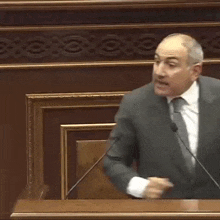 a man in a suit and tie is giving a speech in a parliament while pointing at the camera .