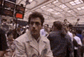 a man in a white coat is standing in a crowd of people in a building .
