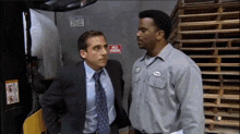 two men standing next to each other with a no smoking sign in the background