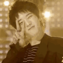 a man in a suit is making a peace sign with his finger .