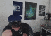 a man wearing a blue hat stands in front of a wall with posters for team liquid