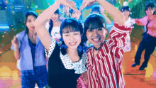 a group of girls are making a heart shape with their hands in front of a sign that says upfront works