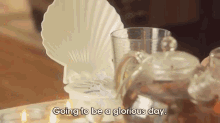 a person is sitting at a table with candles and a glass with the words going to be a glorious day written on it
