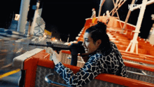 a woman holding a gun on a roller coaster with netflix in the corner