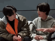 two men are sitting next to each other and talking .