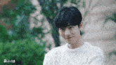 a young man with black hair is wearing a white sweater .