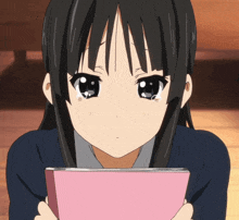 a girl with tears running down her face is holding a pink book