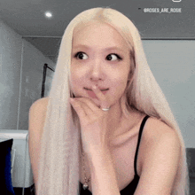 a woman with long blonde hair is wearing a black tank top and a necklace