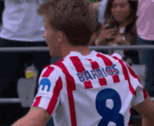 a man wearing a red and white striped jersey with the name barrios on the back
