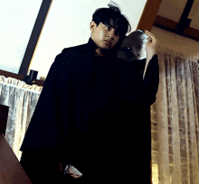a man in a black coat is holding a helmet