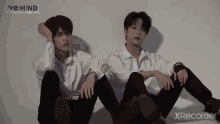a couple of young men are sitting next to each other on the floor .