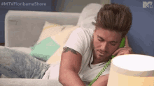 a man is laying on a couch talking on a green corded phone .