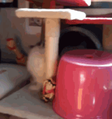 a pink stool is sitting next to a cat tree