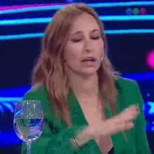 a woman wearing a green jacket is sitting next to a glass of water