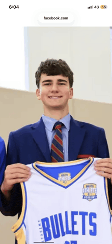a man in a suit and tie is holding a jersey that says bullets on it