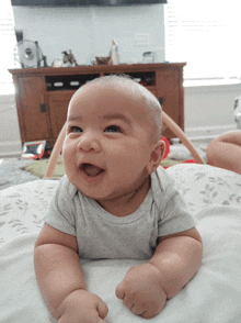 a baby is laying on his stomach and smiling at the camera