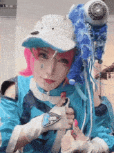 a woman with pink hair and a white hat is holding a blue object