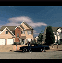 a black car is parked in front of a house in a residential area