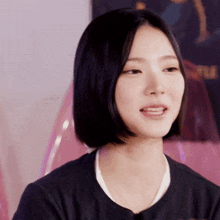 a woman with short black hair is smiling in front of a pink chair