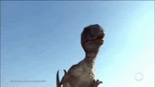 a dinosaur is standing in front of a blue sky with its mouth open .