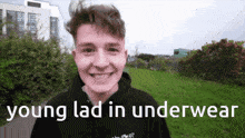 a young man wearing a black hoodie is smiling with the words young lad in underwear below him