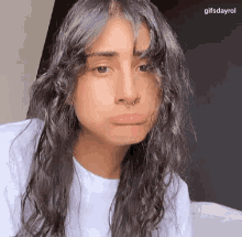 a woman with long curly hair and a nose ring is making a funny face .