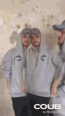 two men in hoodies and hats are standing next to each other .