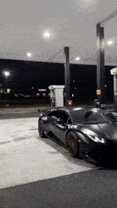 a black sports car is parked at a gas station with a t on it
