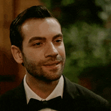 a man in a tuxedo and bow tie smiles