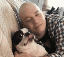 a man with a bald head is holding a small dog