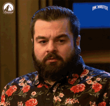 a man with a beard is wearing a floral shirt that says ink master on it