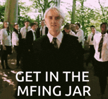 a man in a suit and tie stands in front of a group of people with the words get in the mfing jar on the bottom