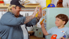 a man and a boy are giving each other a high five in front of a refrigerator that has stickers on it
