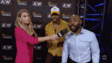 a woman is interviewing two men in front of a wall that says aew on it