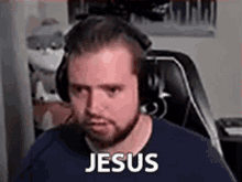 a man with a beard and headphones is sitting in front of a computer .